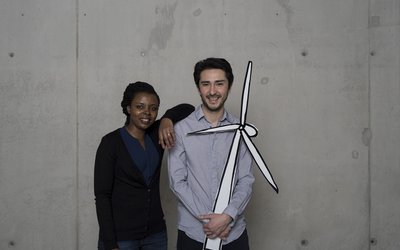 A woman and a man are holding a pinwheel recorded on cardboard.