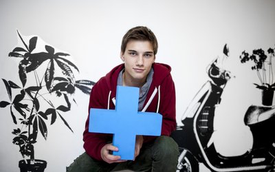 Jugendlicher hält blaues Erasmus Logo in die Kamera
