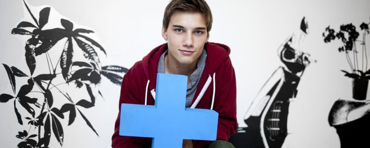 Jugendlicher hält blaues Erasmus Logo in die Kamera