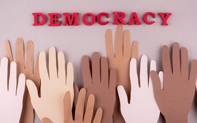 Papiercollage mit Händen und dem Wort "Democracy"