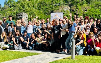 Foto aller Teilnehmerinnen und Teilnehmer des eTwinning-Donauraumseminars 2023. In etwas 50 Teilnehmer/innen stehen mit freudigem Blick und teils gehobenen Armen vor einem grünen Weinhügel.