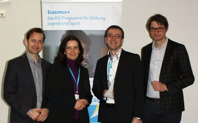 Gruppenfoto mit 3 Männern und einer Frau vor einem Roll Up mit dem Wortlaut Erasmus+