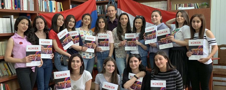 Eine Gruppe von Studierenden hält die neue Ausgabe des Alpen Kaukasus Kurier in Händen.