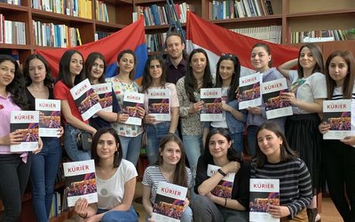 Eine Gruppe von Studierenden hält die neue Ausgabe des Alpen Kaukasus Kurier in Händen.