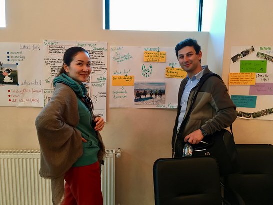 Two scholars in front of flip chart presenting their work