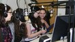 Four young people sitting in front of two microphones in a recording room.