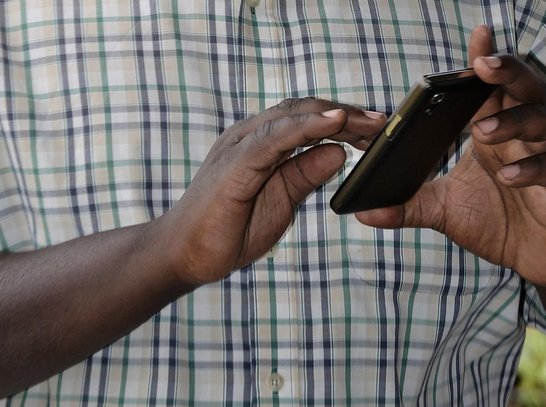 Two hands of a man holding a mobilephone in closeup view