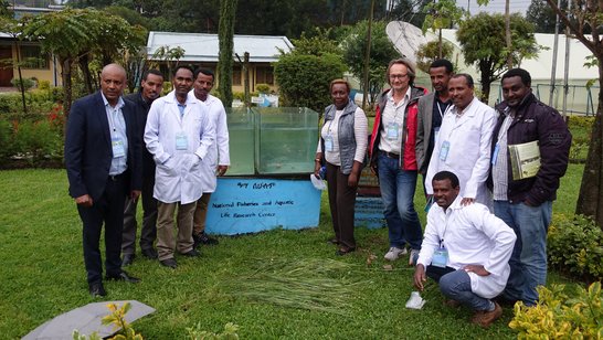 Scientists standing in the premises of the research center and posing next to aquarium 