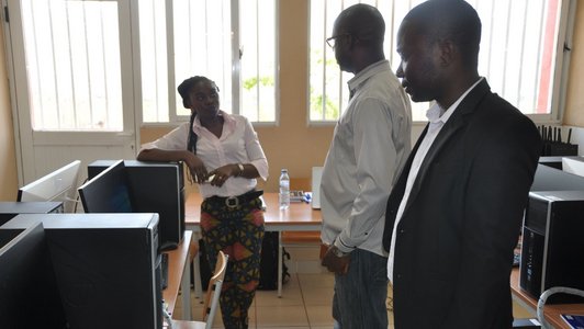 Two men and a woman standing in a computer room looking to each other