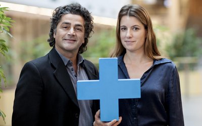 Mann und Frau halten blaues Erasmus Plus Symbol in die Kamera