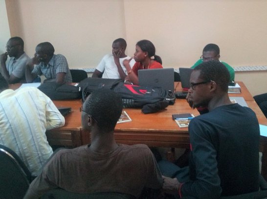 People sitting together around a table and looking in the same direction watching something