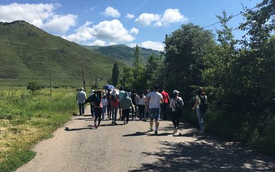 Group of people walking along a street in green hilly surroundings