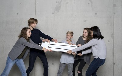 Eine Gruppe von Schülerinnen und Schüler streitet sich um einen Bleistift.