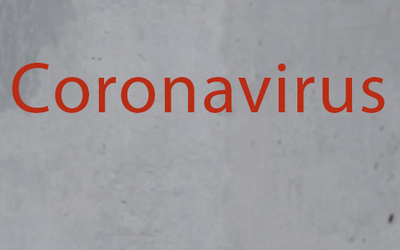Graue Wand mit dem Schriftzug Coronavirus/COVID-19 in roter Farbe
