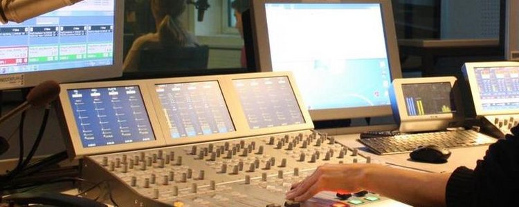 Radio studio with a person's hand operating a mixer.