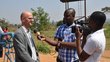 Two men interviewing and filming an other man outdoor