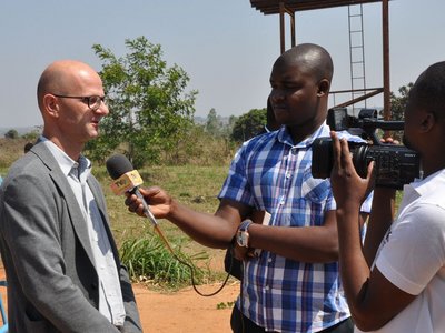 Two men interviewing and filming an other man outdoor