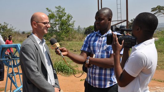 Two men interviewing and filming an other man outdoor