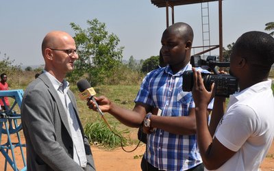 Two men interviewing and filming an other man outdoor