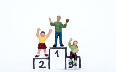 Drei Spielzeugfiguren stehen auf einem gebastelten Podest.