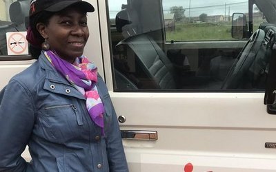 Die APPEAR-Wissenschaftlerin Esther Mukooza aus Uganda vor einem Geländewagen. 