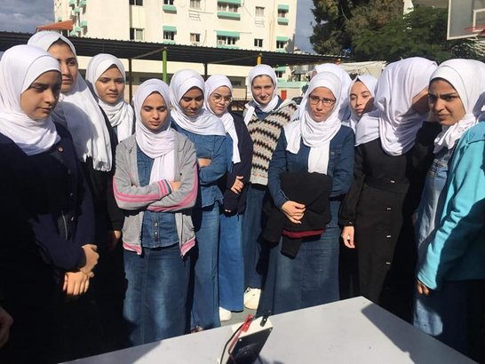 Female high school students inspect solar panel at high school yard
