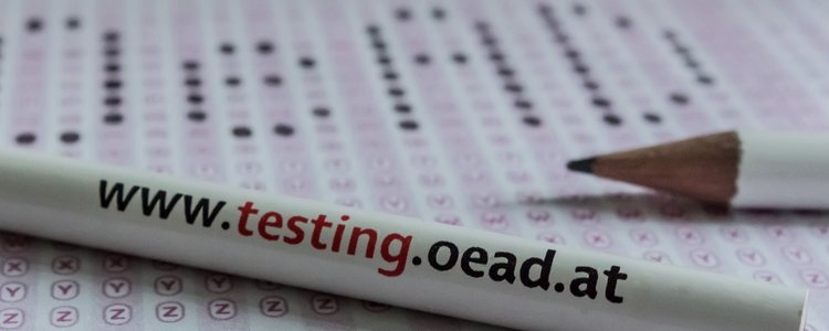 Bleistift mit Aufschrift "OeAD International Testing Services" liegt auf einem Blatt Papier.