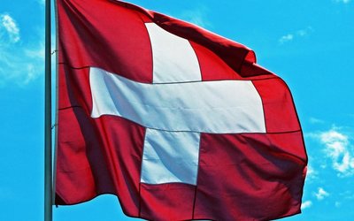 Eine Schweizer Flagge weht bei blauem Himmel im Wind.