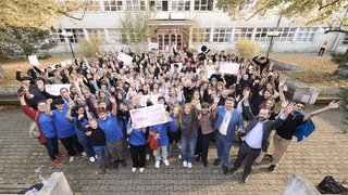 Die Gewinner/innen des Citzizen Science Awards 2024 stehen in einem Hof und präsentieren ihre Schecks.
