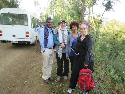 Group of people posing for a picture in front of a white bus