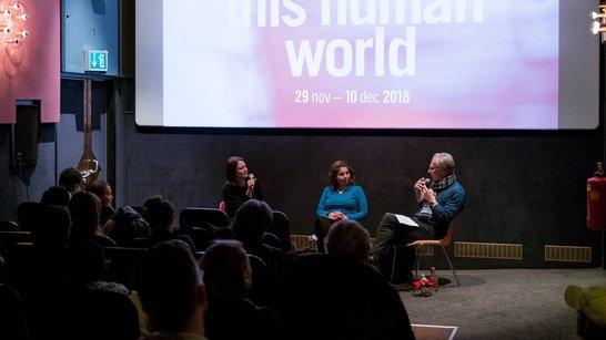 picture shows people in the cinema sitting, listening and watching the two panellists who are sitting in the front of the room