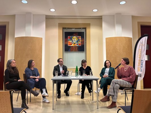 6 Personen rund um Tisch bei Podiumsdiskussion