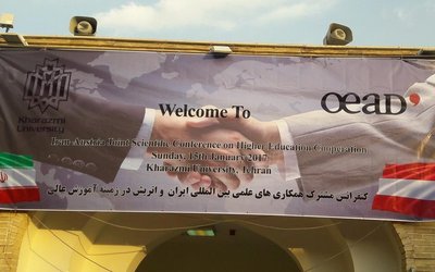 Poster with Iran and Austria flag and OeAD logo hanging on a house wall.