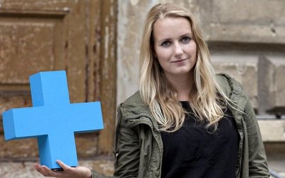 Eine Studentin hält ein blaues ErasmusPlus-Symbol mit einer Hand.