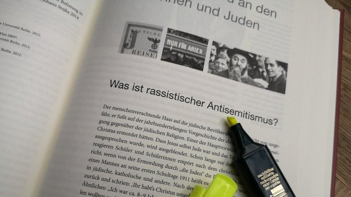 Ein offenes Buch mit einem gelbfarbigen Textmarker. Der Text beinhaltet eine Einführung in das Thema Antisemitismus