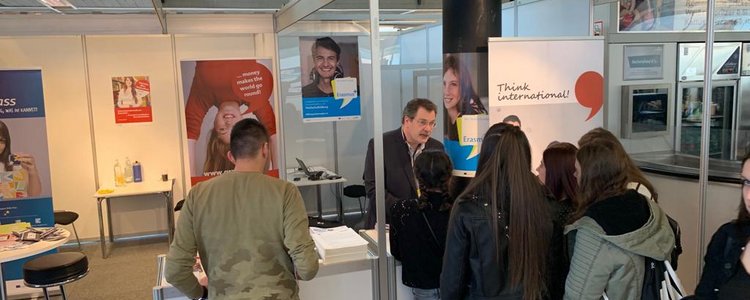 Ein Mitarbeiter des OeAD berät Schülerinnen und Schüler am Messestand.