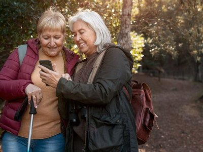 Senior woman showing her friend something on her smartphone while being on a trip