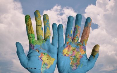 Zwei bemalte Hände, auf denen Weltkarte sichtbar 