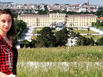 Die Studentin Luiza Spahiu posiert im Schönbrunner Schloßpark mit dem Schloß im Hintergrund.