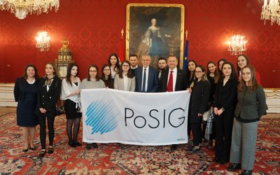 Eine Gruppe von etwa 15 internationalen Studierenden posiert gemeinsam mit Herrn Bundespräsident Van der Bellen für ein Foto.