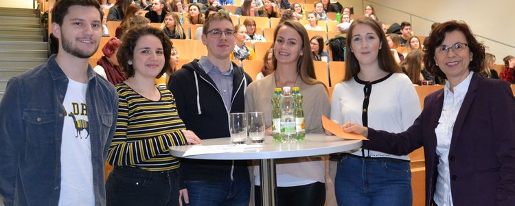 Sechs männliche und weibliche Studierende der FH Burgenland stehe bei einem Tisch. 
