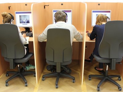 3 people with their backs turned are working on their PCs