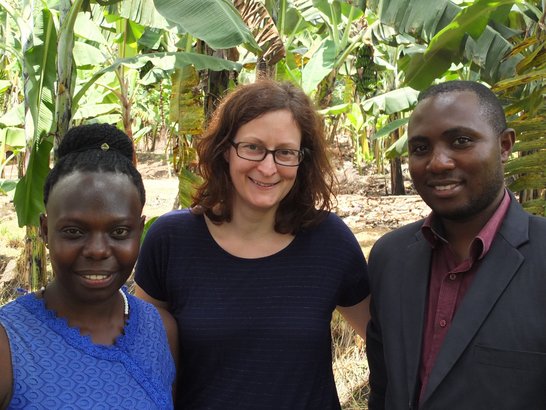 Two APPEAR scholars and one APPEAR representative posing for a photo in front of banana plants