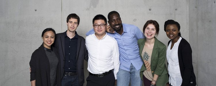 Group of alumni in front of a concrete wall