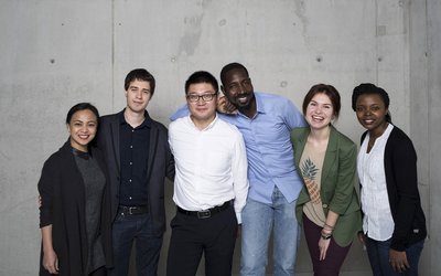 Group of alumni in front of a concrete wall