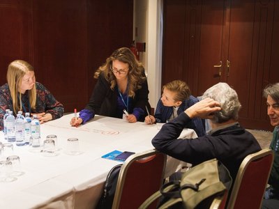 Fünf Personen sitzen an einem Tisch und diskutieren im Rahmen eines Workshops.
