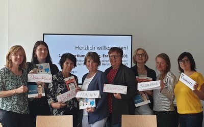 Group photo with ladies, they are holding pieces of paper with different countries written on them.