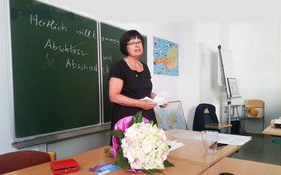 Margarete Kernegger steht in einem Klassenzimmer vor der Tafel.