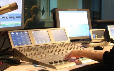 Radiostudio mit Hand einer Person, die ein Mischpult bedient.