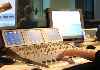 Radiostudio mit Hand einer Person, die ein Mischpult bedient.